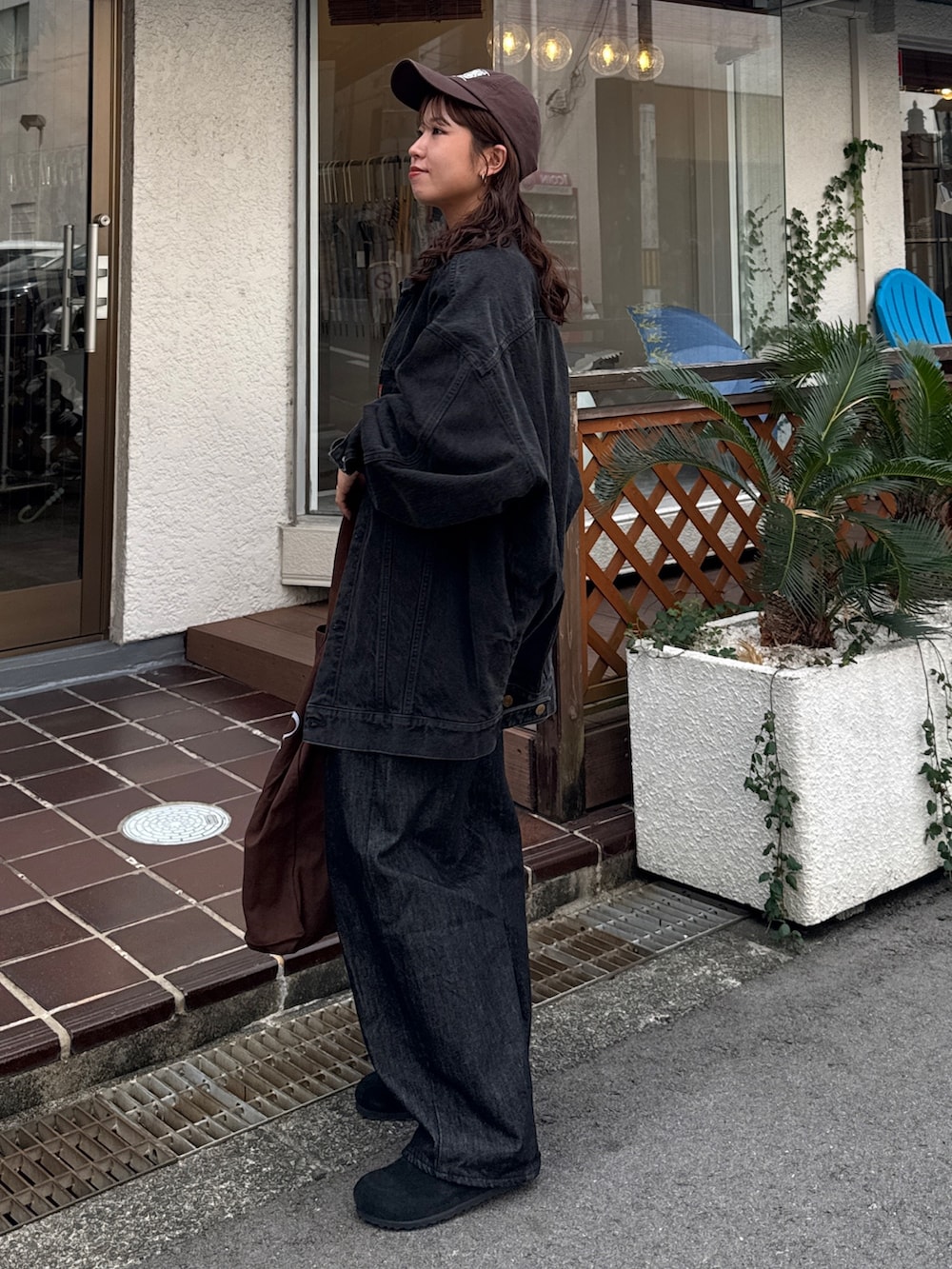 ブラック系のデニムジャケット、ブラック系のデニムパンツ、ブラウン系のトートバッグを着用したレディースの秋コーディネートの4枚目の写真