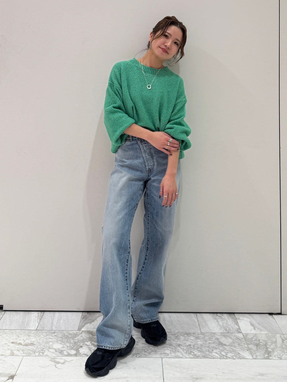 ブルー系のデニムパンツ、グリーン系のニット/セーター、シルバー系のネックレスを着用したレディースの冬コーディネートの8枚目の写真