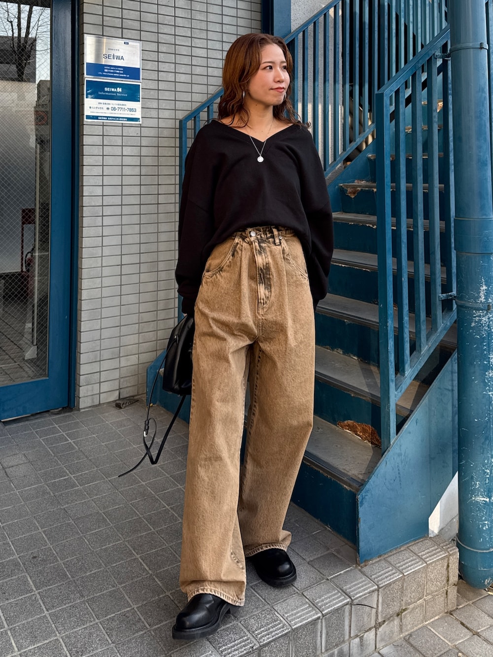 ブラウン系のデニムパンツ、ブラック系のスウェットを着用したレディースの冬コーディネートの6枚目の写真