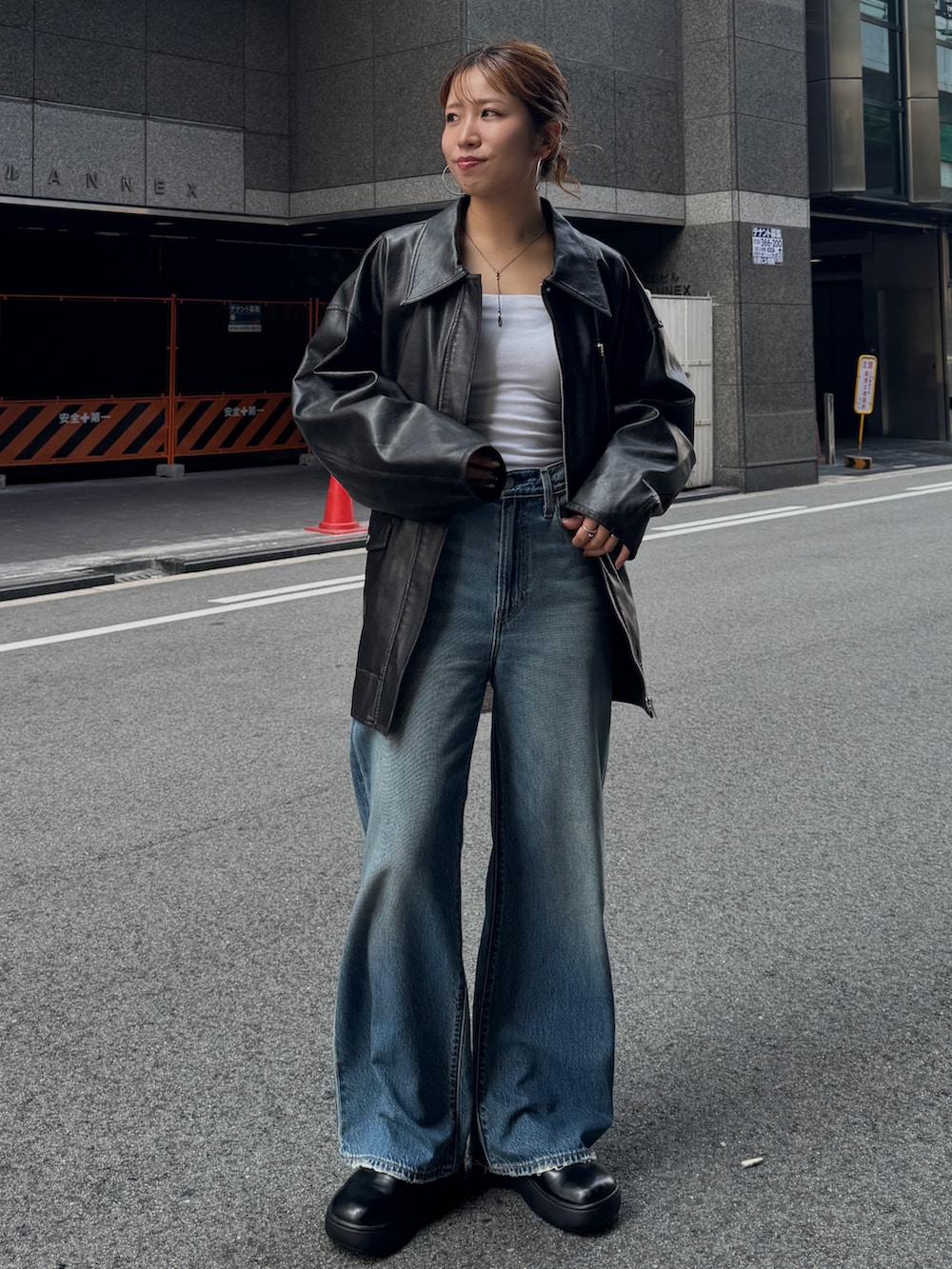ブラック系のブルゾン、ブルー系のデニムパンツを着用したレディースの秋コーディネートの2枚目の写真