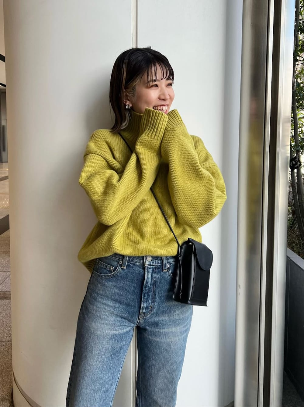 ブルー系のデニムパンツ、グリーン系のニット/セーターを着用したレディースの冬コーディネートの2枚目の写真