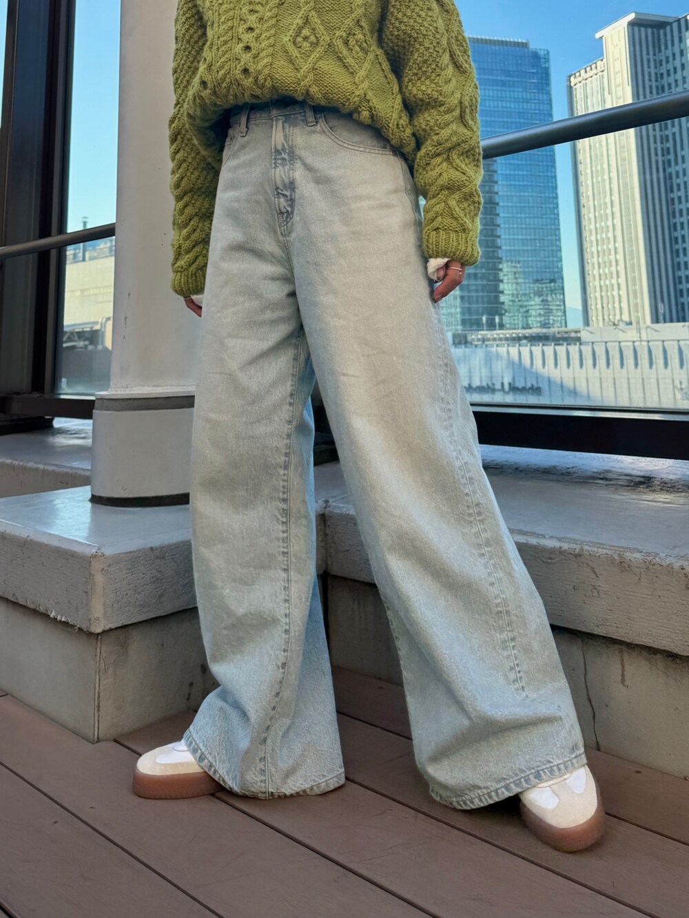 グリーン系のニット/セーター、ホワイト系のTシャツ/カットソー、ブルー系のデニムパンツを着用したレディースの冬コーディネートの9枚目の写真