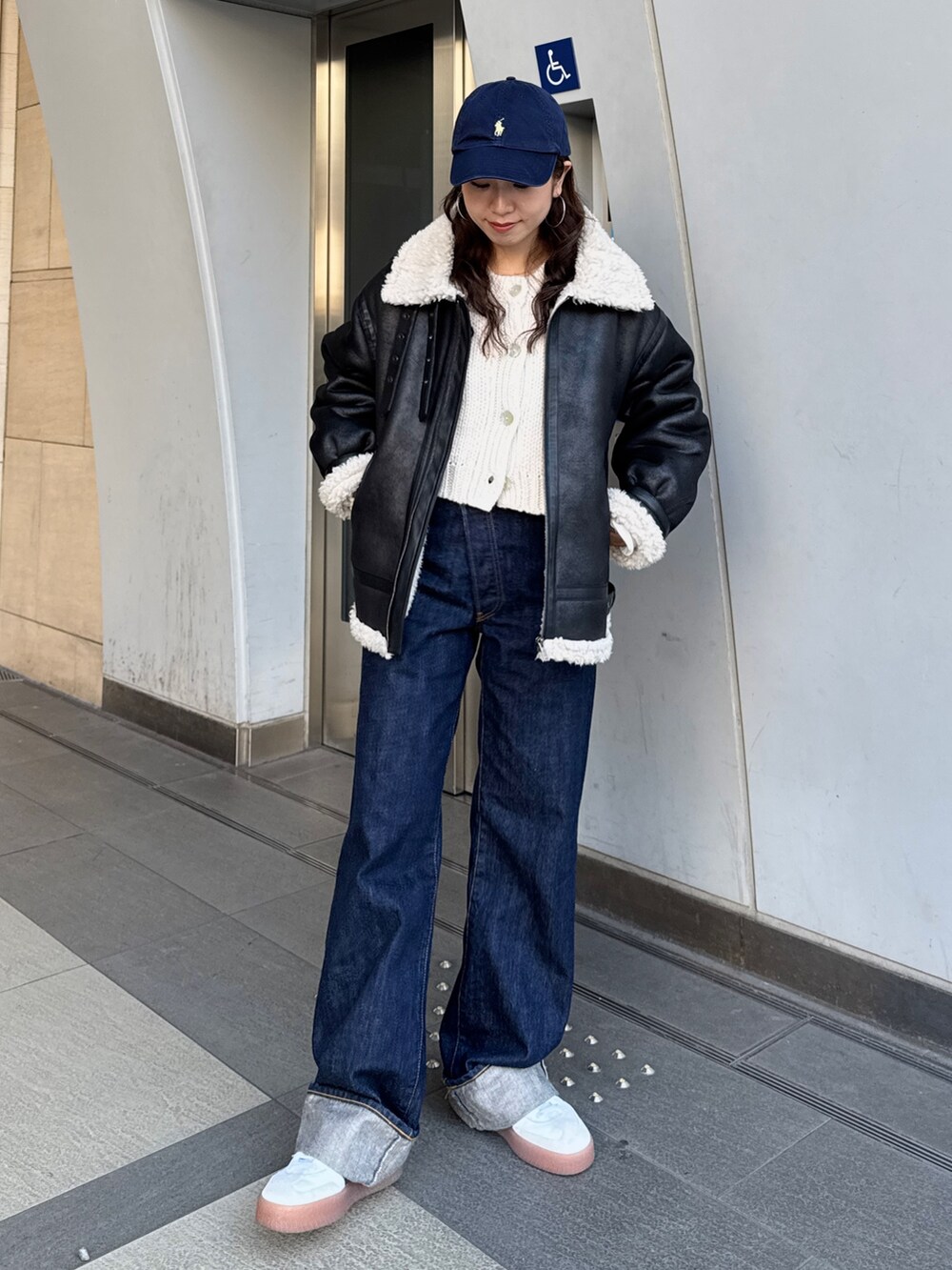 ブルー系のデニムパンツ、ホワイト系のカーディガン/ボレロ、ブラック系のブルゾンを着用したレディースの冬コーディネートの2枚目の写真