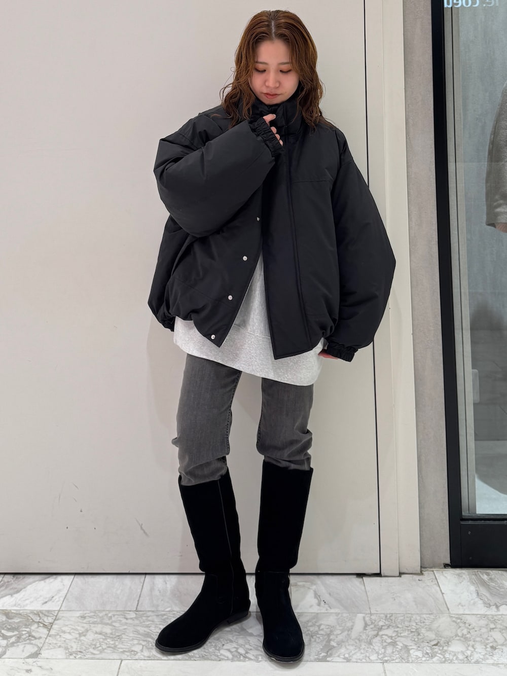 ブラック系のブルゾン、グレー系のスウェット、ブラック系のデニムパンツを着用したレディースの冬コーディネートの2枚目の写真