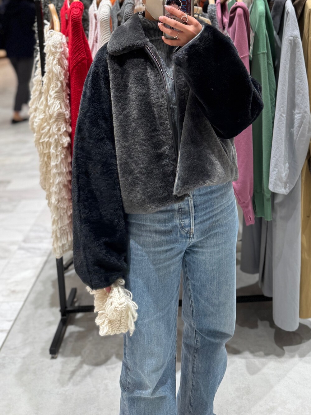 グレー系のブルゾン、グレー系のニット/セーター、ブルー系のデニムパンツを着用したレディースの秋コーディネートの2枚目の写真