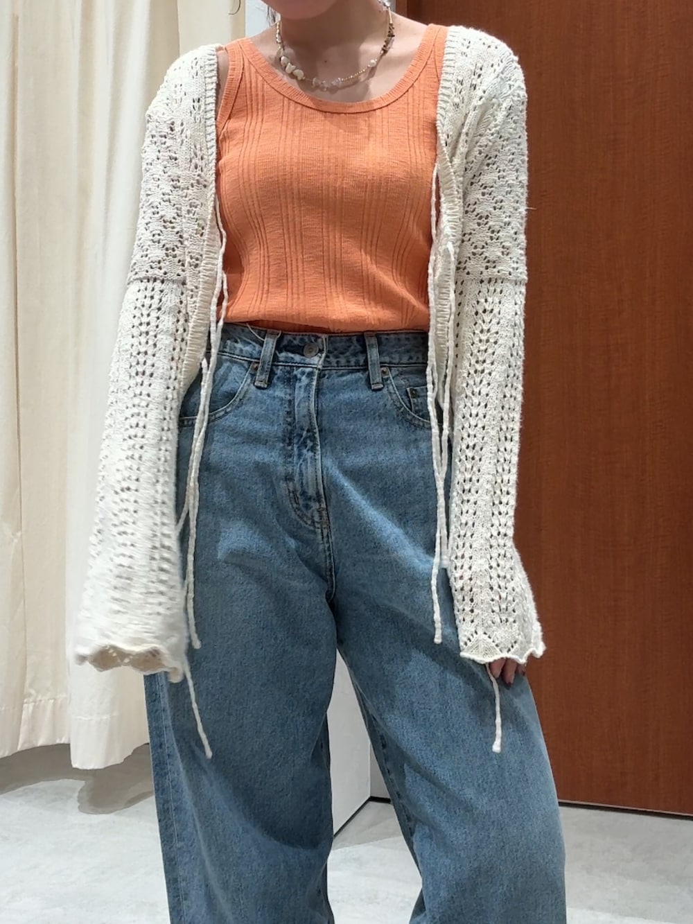 ブルー系のデニムパンツ、オレンジ系のタンクトップ、ホワイト系のカーディガン/ボレロを着用したレディースの春コーディネートの9枚目の写真
