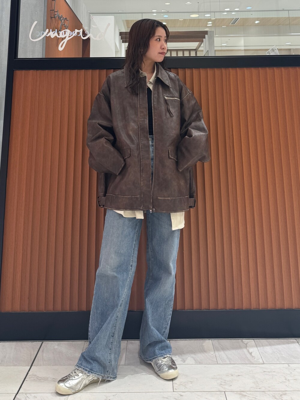 ブラウン系のブルゾン、ホワイト系のシャツ/ブラウス、ブルー系のデニムパンツを着用したレディースの秋コーディネートの5枚目の写真