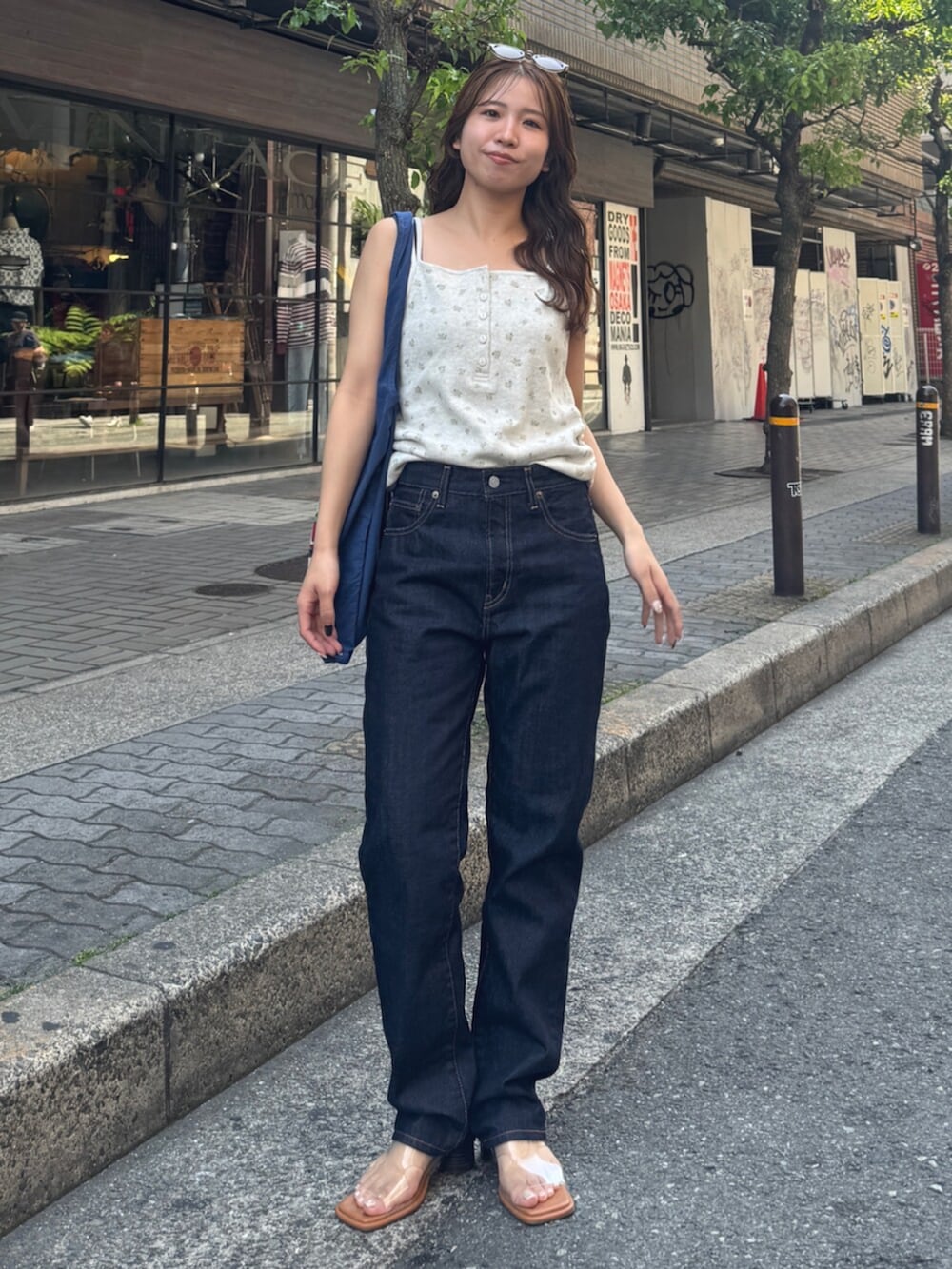 ブルー系のデニムパンツ、その他のサンダル、ブルー系のトートバッグを着用したレディースの春コーディネートの3枚目の写真