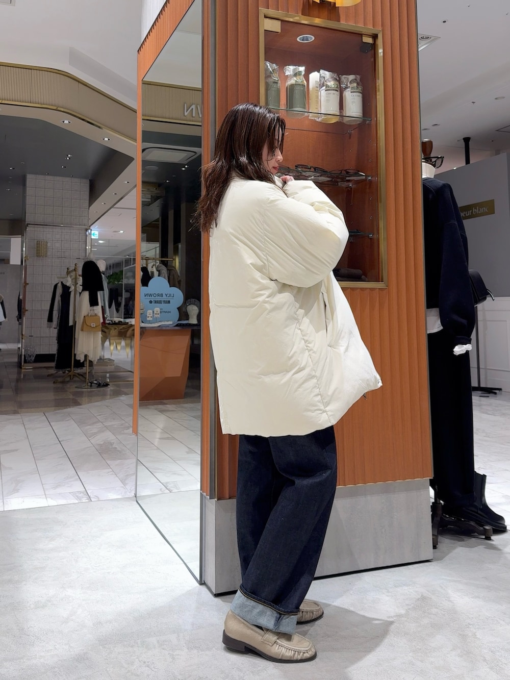 ホワイト系のダウンジャケット/コート、グレー系のニット/セーター、ブルー系のデニムパンツを着用したレディースの冬コーディネートの7枚目の写真