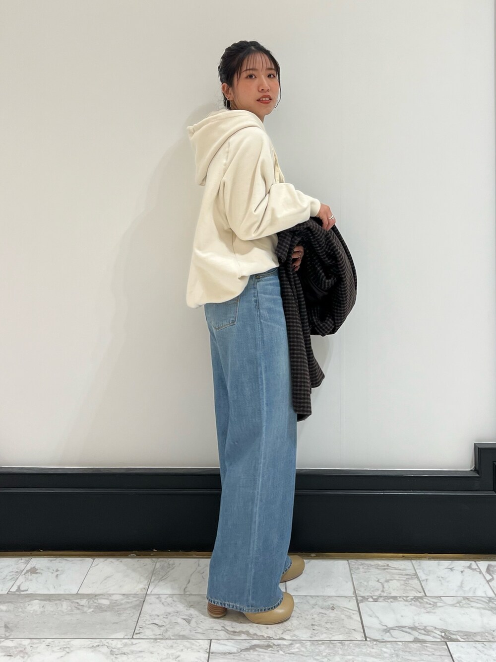 ホワイト系のパーカー、ブルー系のデニムパンツ、ベージュ系のブーツを着用したレディースの冬コーディネートの5枚目の写真