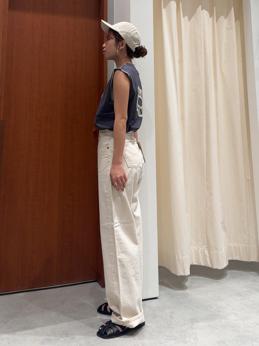 ホワイト系のデニムパンツ、グレー系のタンクトップ、ブラック系のサンダルを着用したレディースの春コーディネートの5枚目の写真