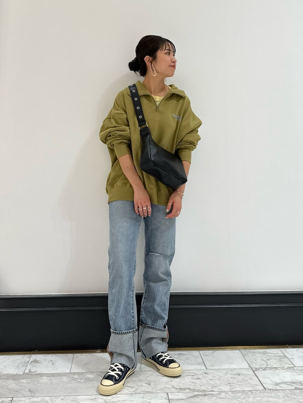 グリーン系のスウェット、ブラック系のショルダーバッグ、イエロー系のTシャツ/カットソーを着用したレディースの冬コーディネートの2枚目の写真