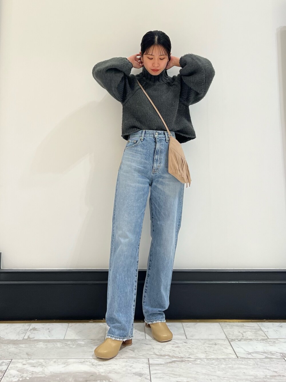 ブルー系のデニムパンツ、グレー系のニット/セーター、ベージュ系のブーツを着用したレディースの秋コーディネートの6枚目の写真