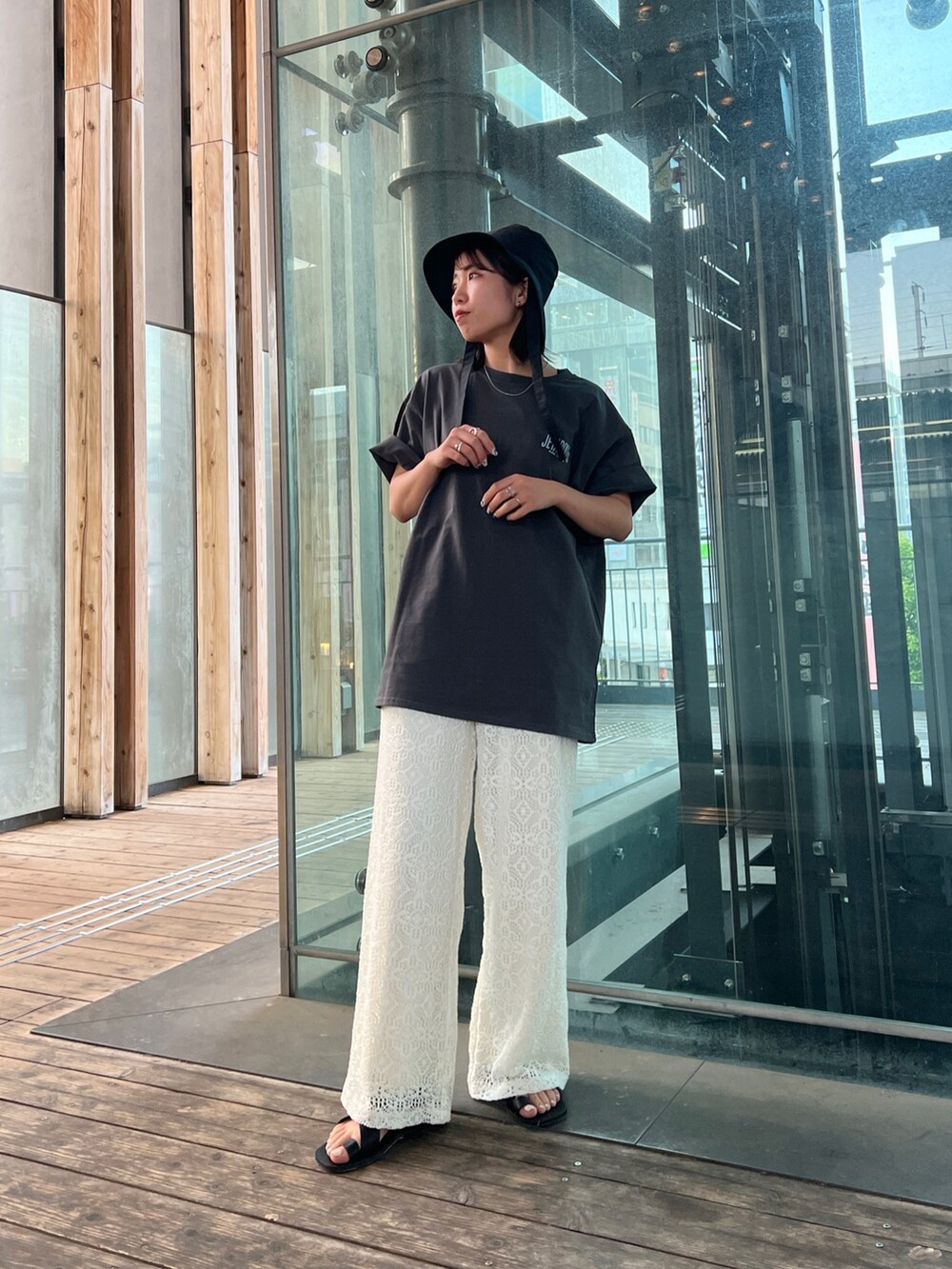 グレー系のTシャツ/カットソー、ホワイト系のその他パンツ、ブラック系のサンダルを着用したレディースの春コーディネートの2枚目の写真