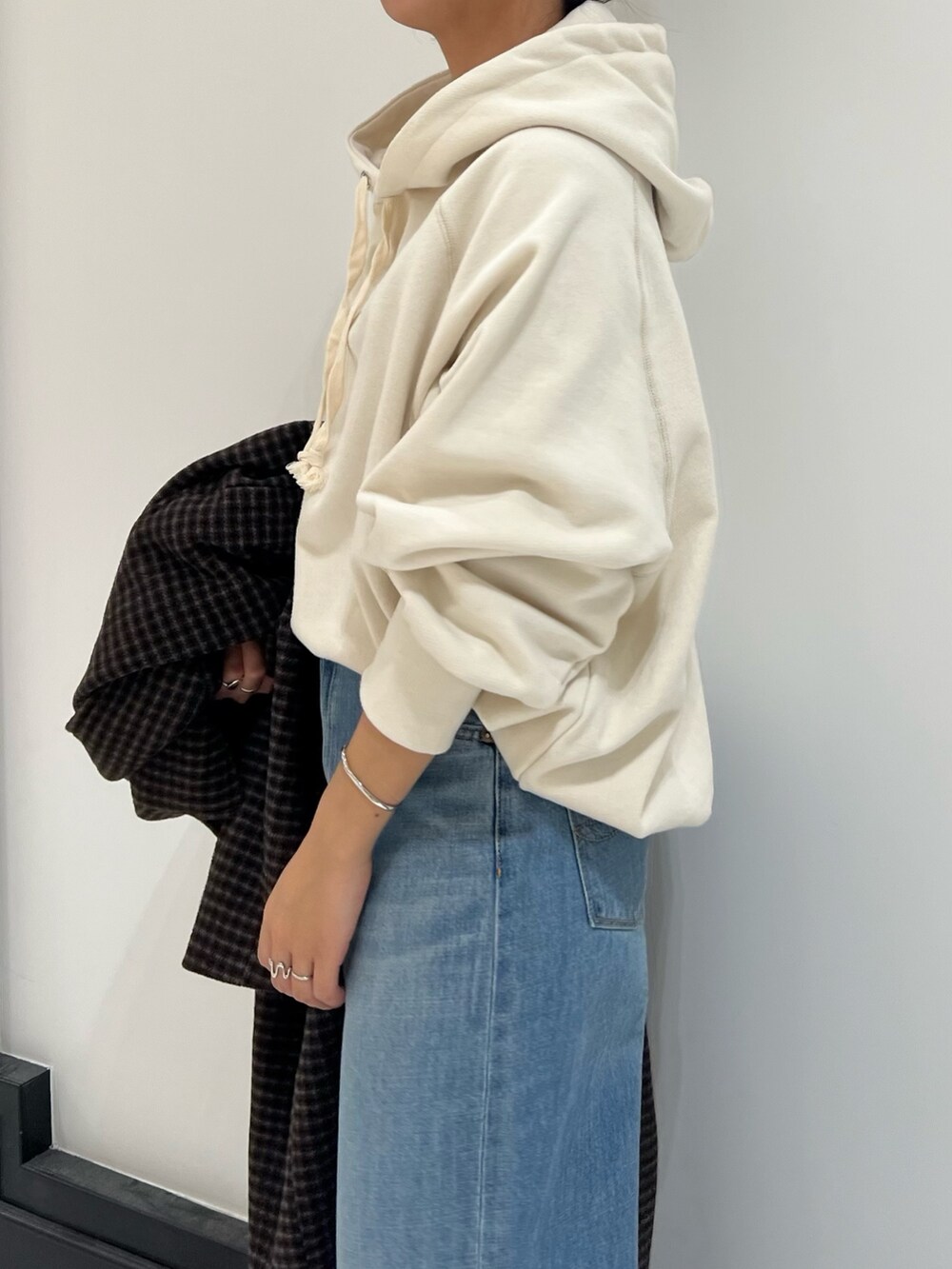 ホワイト系のパーカー、ブルー系のデニムパンツ、ベージュ系のブーツを着用したレディースの冬コーディネートの3枚目の写真