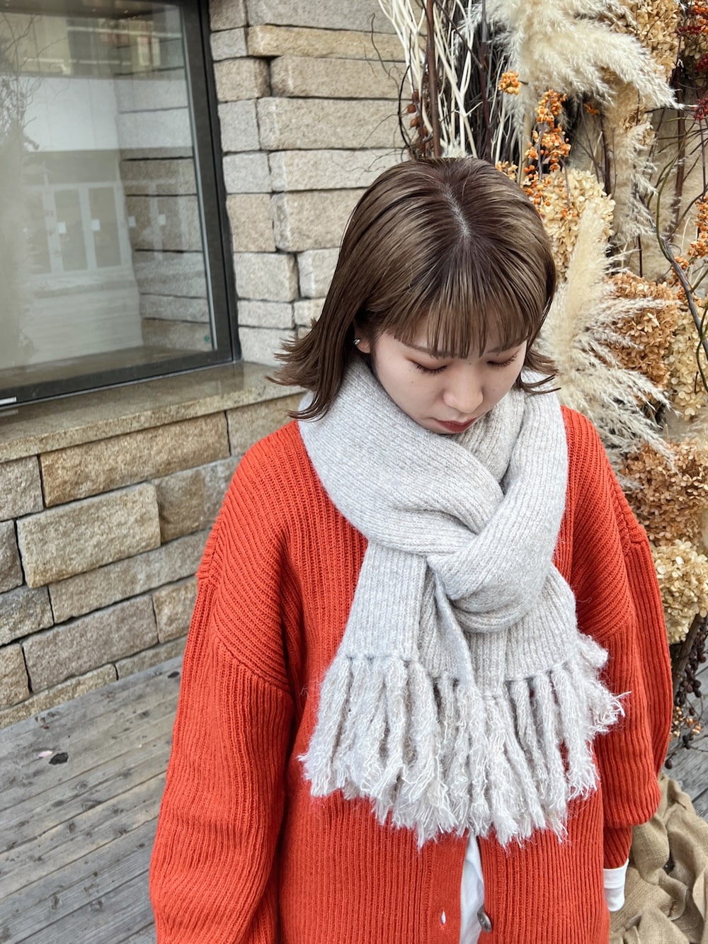 オレンジ系のカーディガン/ボレロ、ブルー系のデニムパンツを着用したレディースの秋コーディネートの5枚目の写真