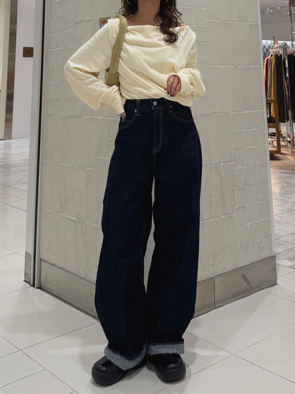 ブルー系のデニムパンツ、ホワイト系のTシャツ/カットソー、グリーン系のハンドバッグを着用したレディースの冬コーディネートの2枚目の写真