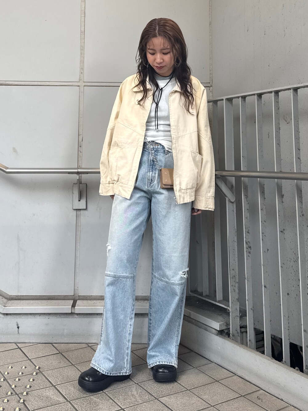 ブルー系のデニムパンツ、ベージュ系のブルゾン、ホワイト系のTシャツ/カットソーを着用したレディースの冬コーディネートの2枚目の写真