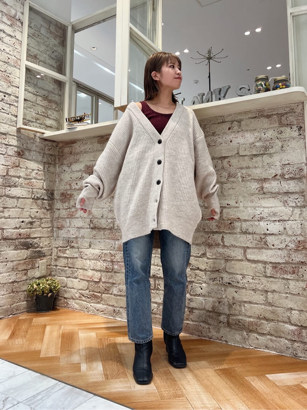 ブラック系のブーツ、ブルー系のデニムパンツ、ホワイト系のカーディガン/ボレロを着用したレディースの秋コーディネートの3枚目の写真