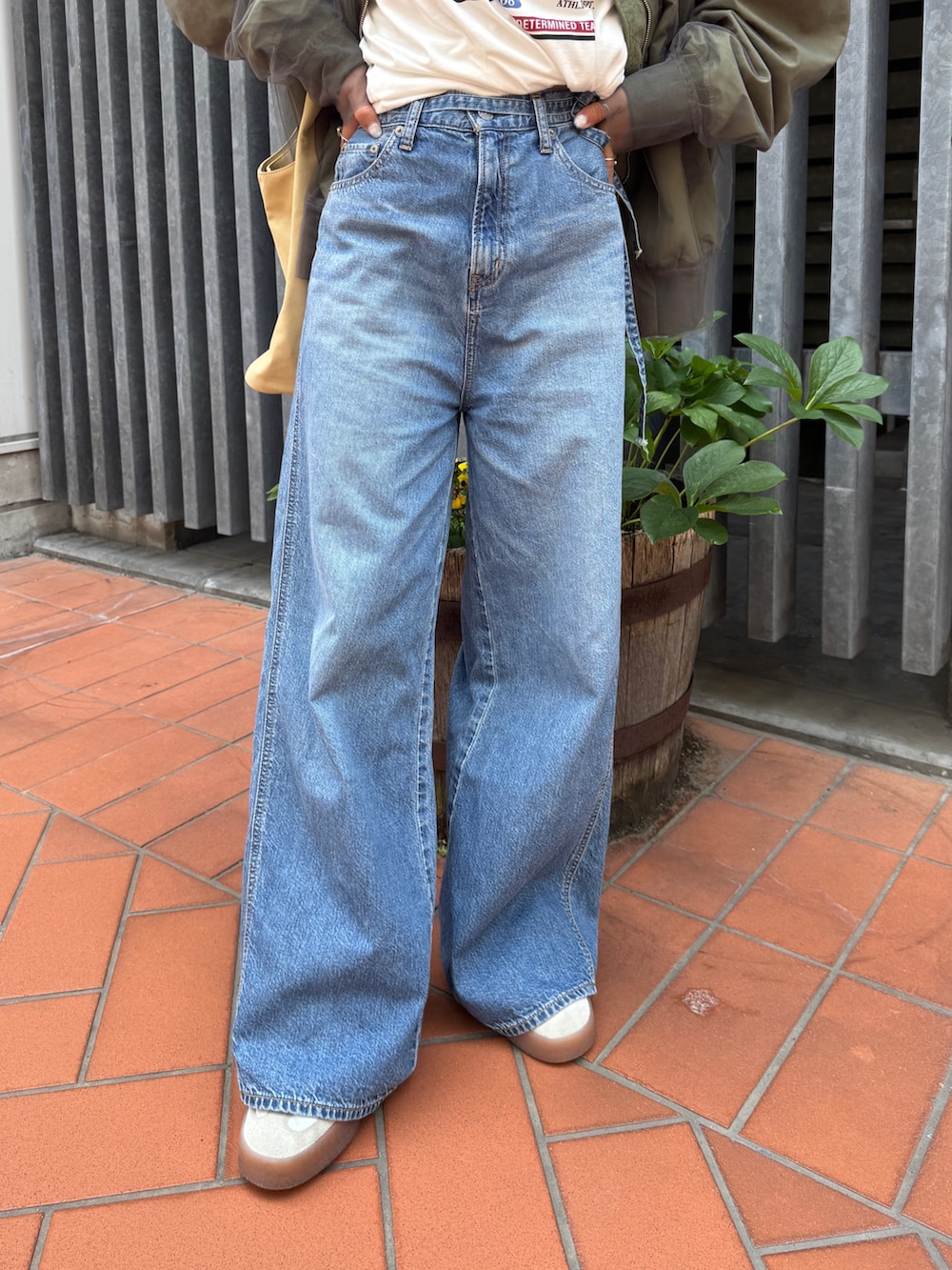 ベージュ系のトートバッグ、ホワイト系のタンクトップ、ブルー系のデニムパンツを着用したレディースの夏コーディネートの9枚目の写真