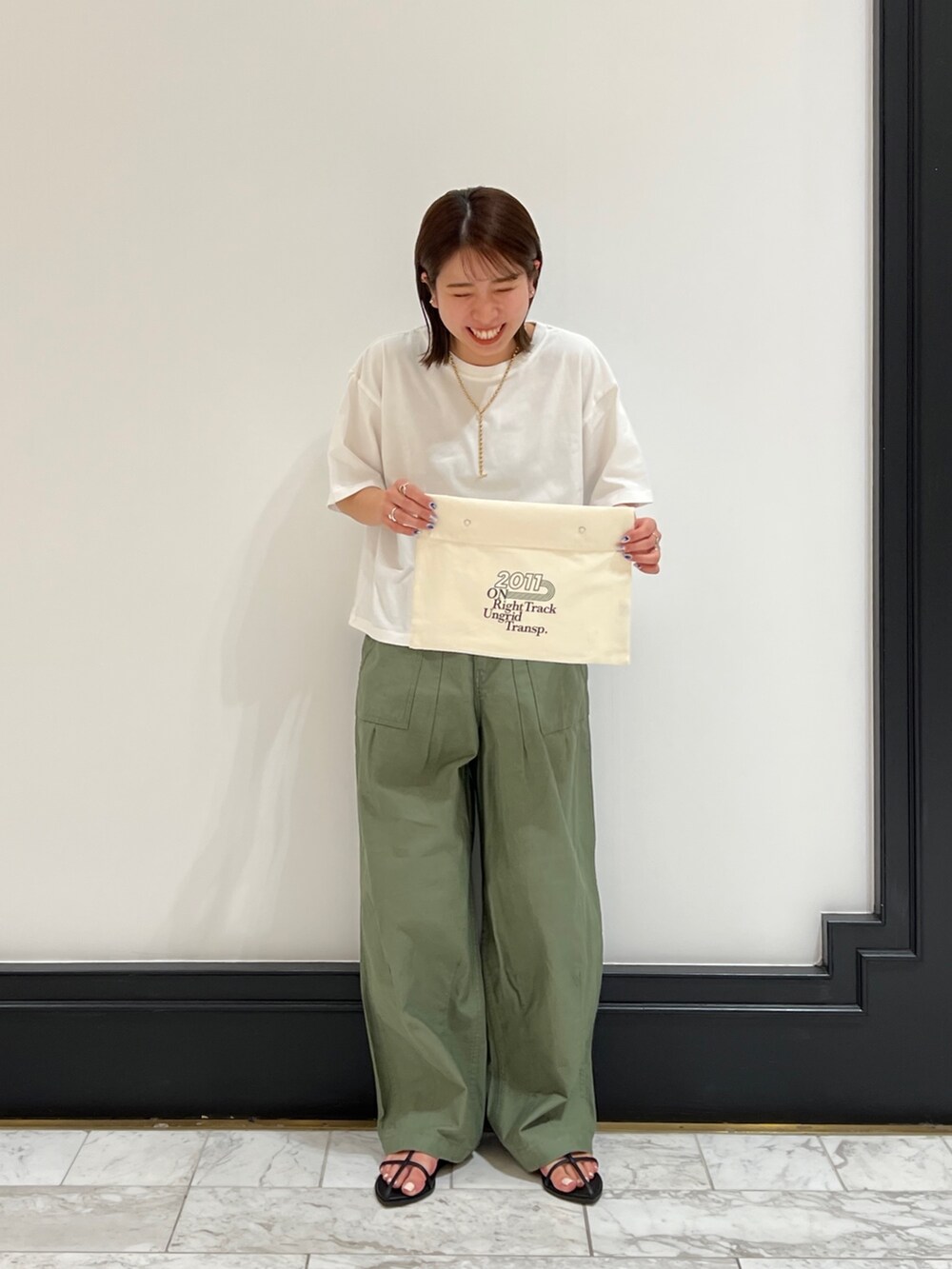 ベージュ系のその他パンツ、ブラック系のサンダル、イエロー系のネックレスを着用したレディースの春コーディネートの7枚目の写真