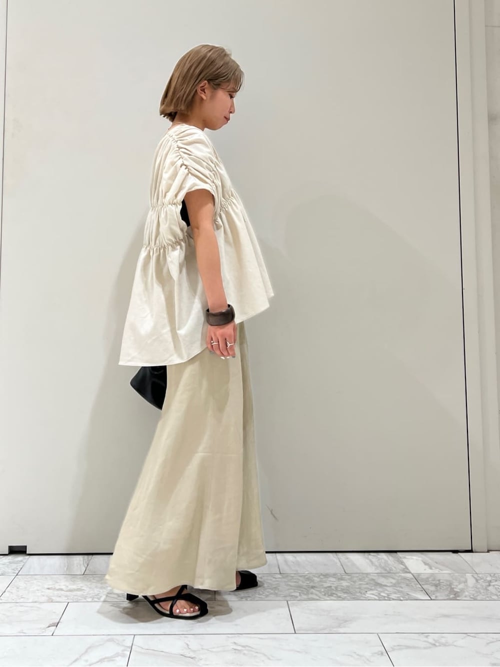 ブラック系のサンダル、ベージュ系のスカート、ホワイト系のシャツ/ブラウスを着用したレディースの夏コーディネートの4枚目の写真