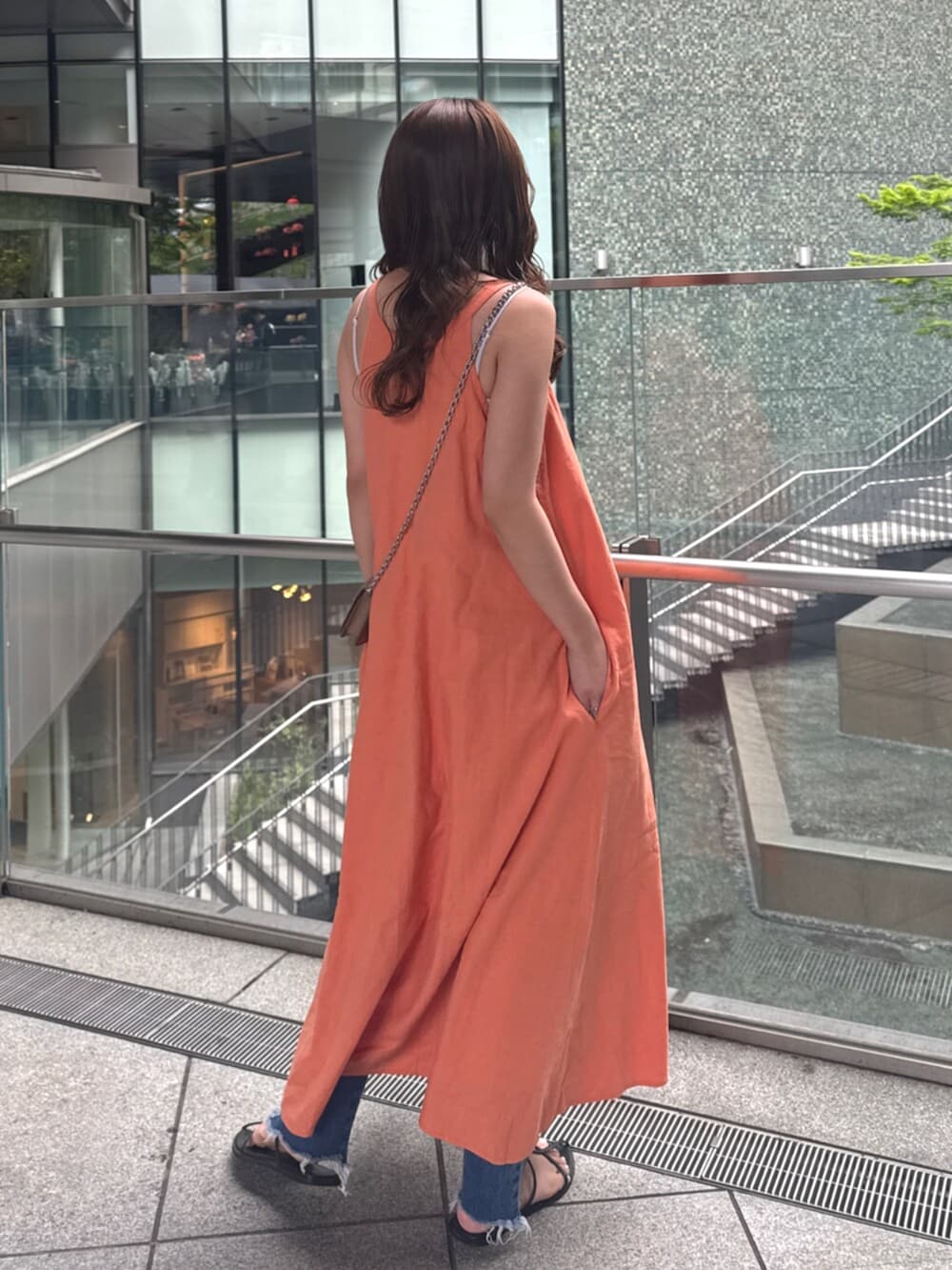 ブルー系のデニムパンツ、オレンジ系のワンピースを着用したレディースの春コーディネートの5枚目の写真
