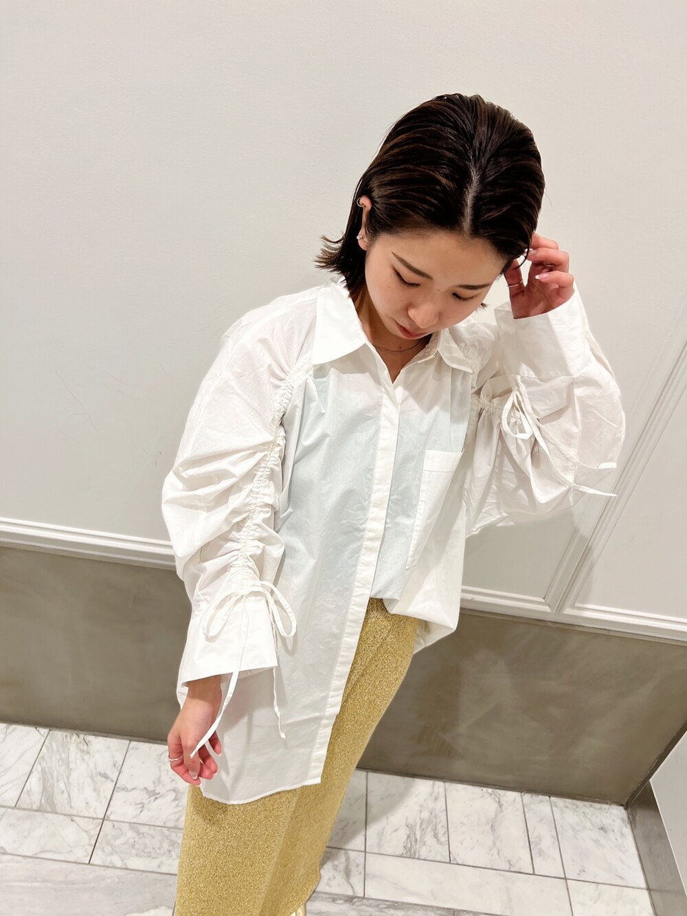 ホワイト系のシャツ/ブラウス、イエロー系のパンプス、ベージュ系のスカートを着用したレディースの冬コーディネートの7枚目の写真