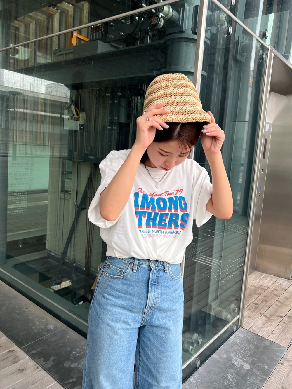 ホワイト系のTシャツ/カットソー、ホワイト系のサンダル、ブルー系のデニムパンツを着用したレディースの春コーディネートの9枚目の写真
