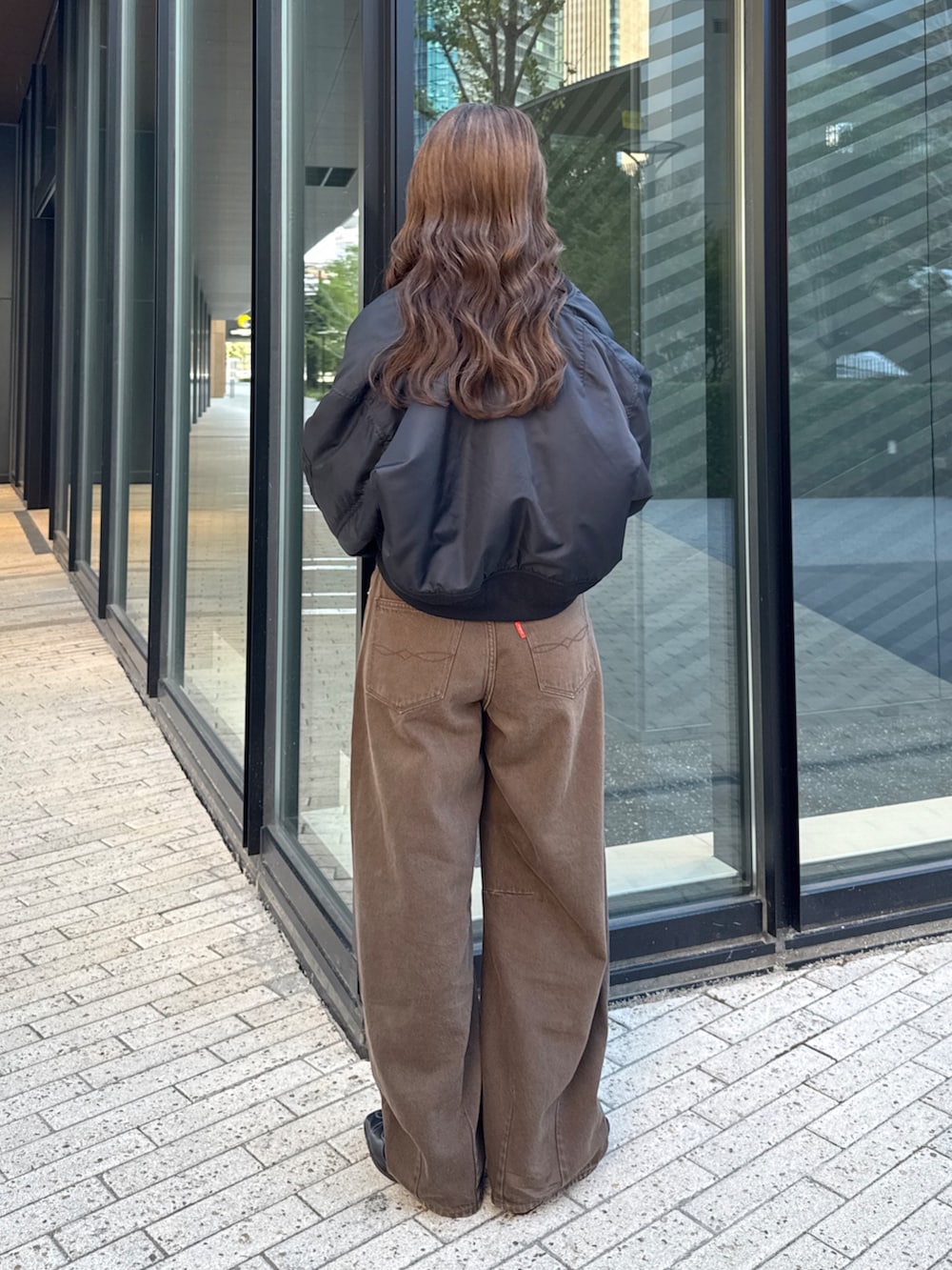ブラウン系のデニムパンツ、ホワイト系のTシャツ/カットソー、ブラック系のMA-1を着用したレディースの秋コーディネートの5枚目の写真