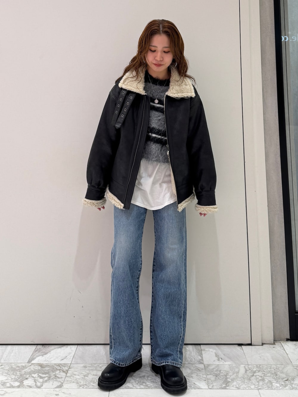 ブラック系のニット/セーター、ホワイト系のTシャツ/カットソー、ブラック系のブーツを着用したレディースの冬コーディネートの7枚目の写真