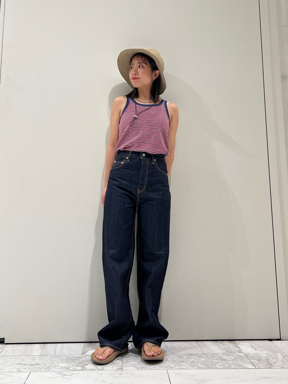 ブルー系のデニムパンツ、ブルー系のタンクトップ、ホワイト系のキャミソールを着用したレディースの夏コーディネートの5枚目の写真