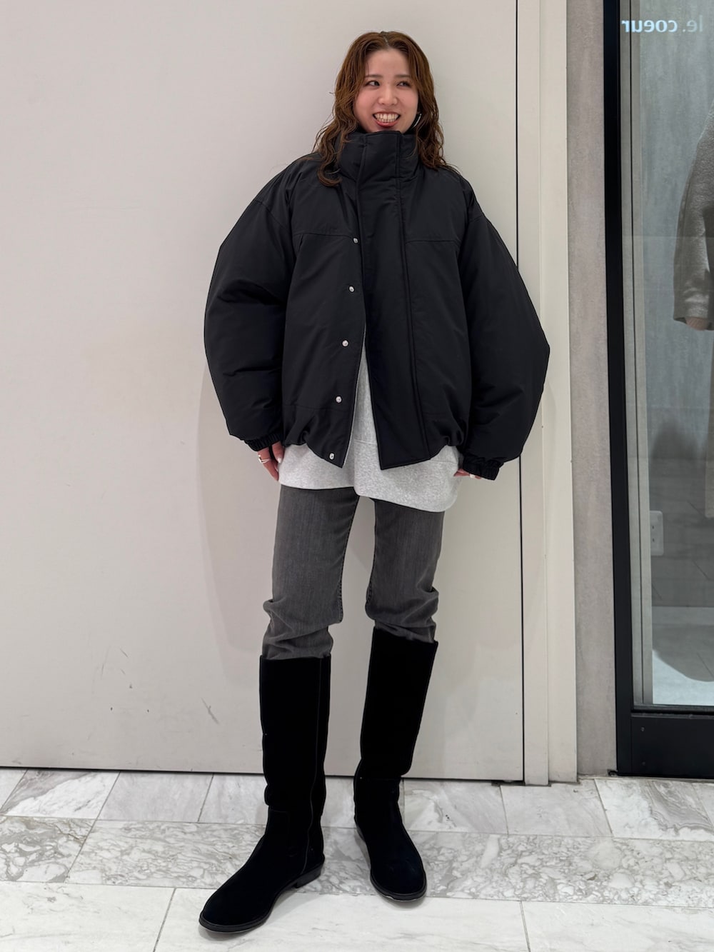 ブラック系のブルゾン、グレー系のスウェット、ブラック系のデニムパンツを着用したレディースの冬コーディネートの6枚目の写真