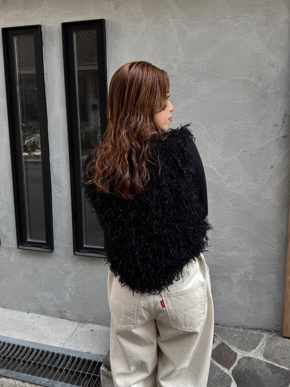 ホワイト系のデニムパンツ、ブラック系のニット/セーター、ブラック系のTシャツ/カットソーを着用したレディースの冬コーディネートの7枚目の写真