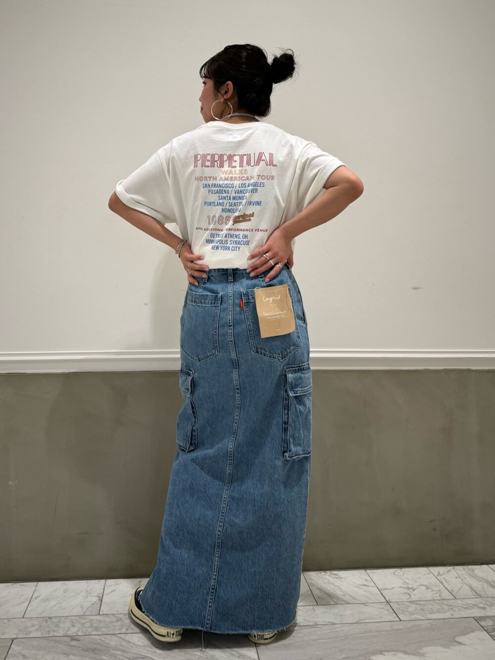 ブルー系のデニムスカート、ホワイト系のTシャツ/カットソー、ブルー系のスニーカーを着用したレディースの春コーディネートの2枚目の写真