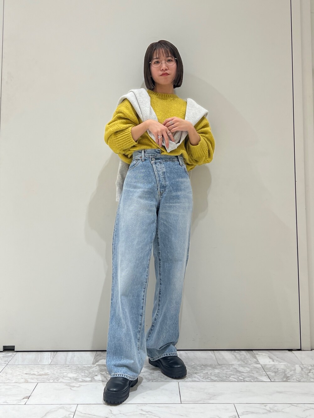 ブルー系のデニムパンツ、イエロー系のニット/セーター、グレー系のスウェットを着用したレディースの冬コーディネートの3枚目の写真