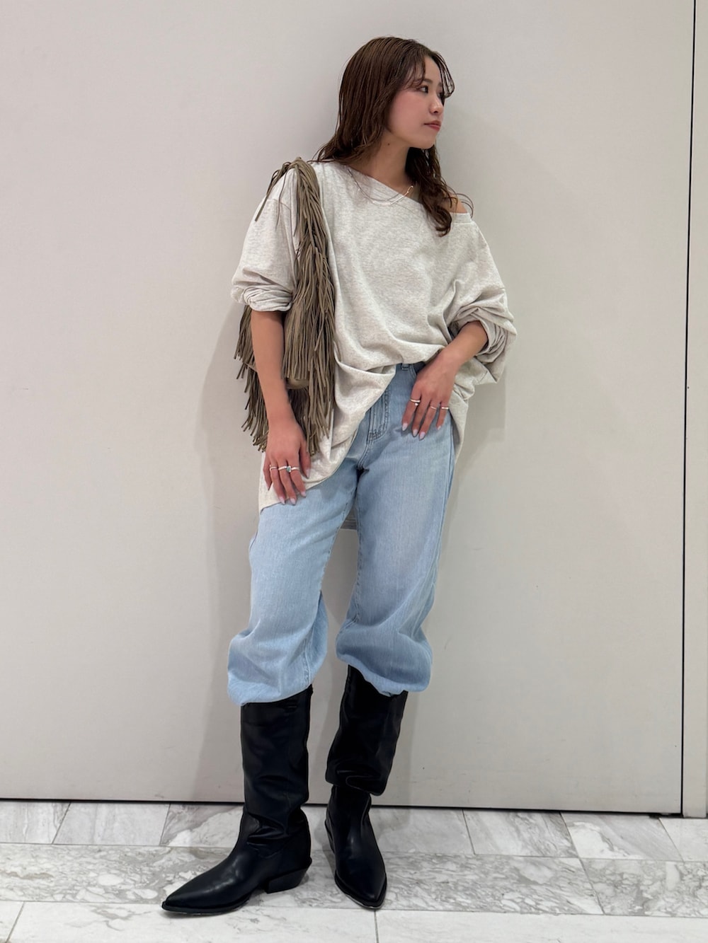 グレー系のTシャツ/カットソー、ベージュ系のハンドバッグ、ブルー系のデニムパンツを着用したレディースの春コーディネートの6枚目の写真