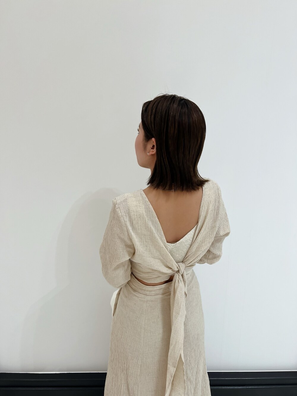 ホワイト系のベスト、ホワイト系のワンピース、ホワイト系のハンドバッグを着用したレディースの春コーディネートの9枚目の写真