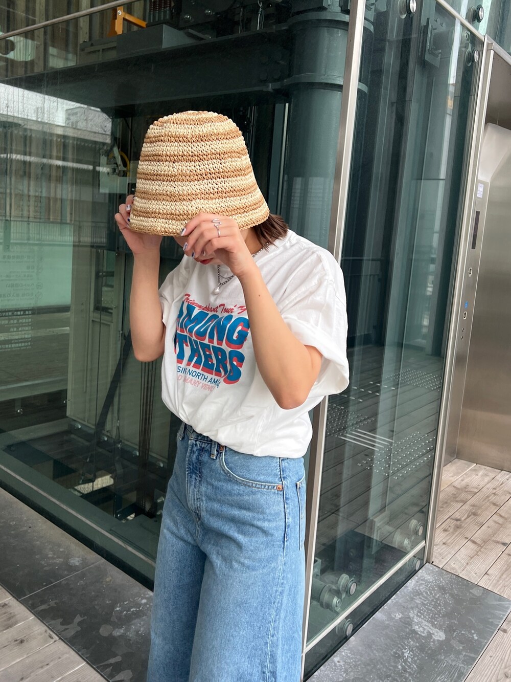 ホワイト系のTシャツ/カットソー、ホワイト系のサンダル、ブルー系のデニムパンツを着用したレディースの春コーディネートの8枚目の写真
