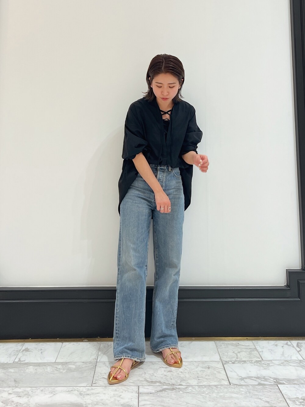 ブラック系のシャツ/ブラウス、ブルー系のデニムパンツ、イエロー系のサンダルを着用したレディースの春コーディネートの2枚目の写真