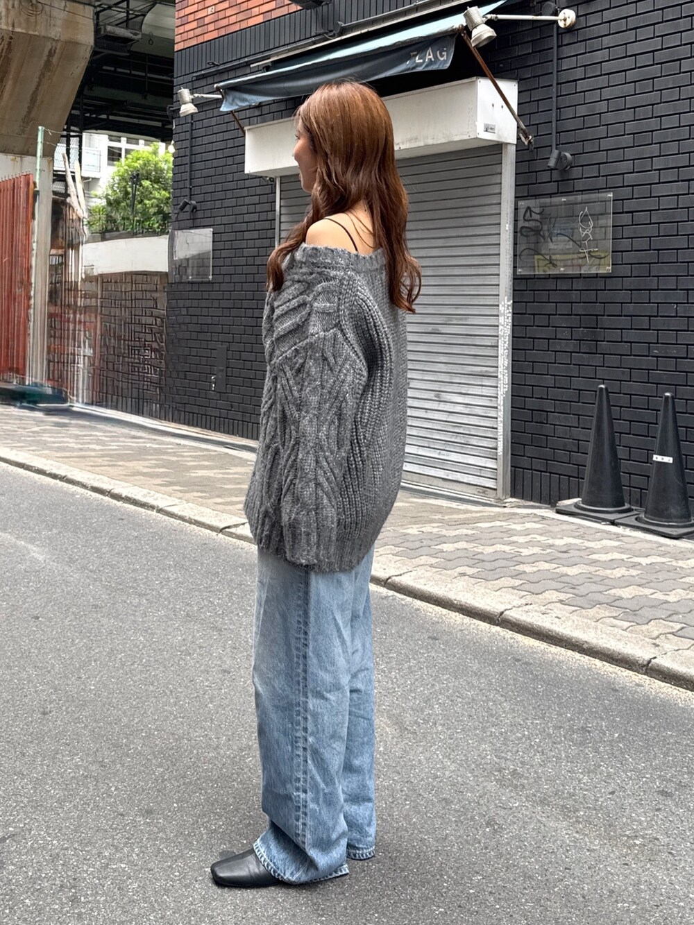 グレー系のニット/セーター、ブルー系のデニムパンツ、ブラック系のサンダルを着用したレディースの秋コーディネートの4枚目の写真