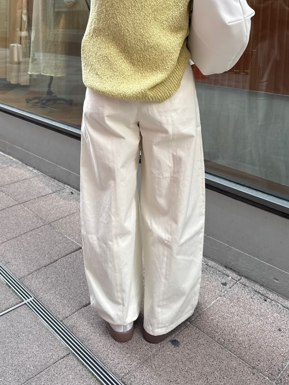 ホワイト系のチノパンツ、グリーン系のニット/セーター、ホワイト系のショルダーバッグを着用したレディースの冬コーディネートの9枚目の写真