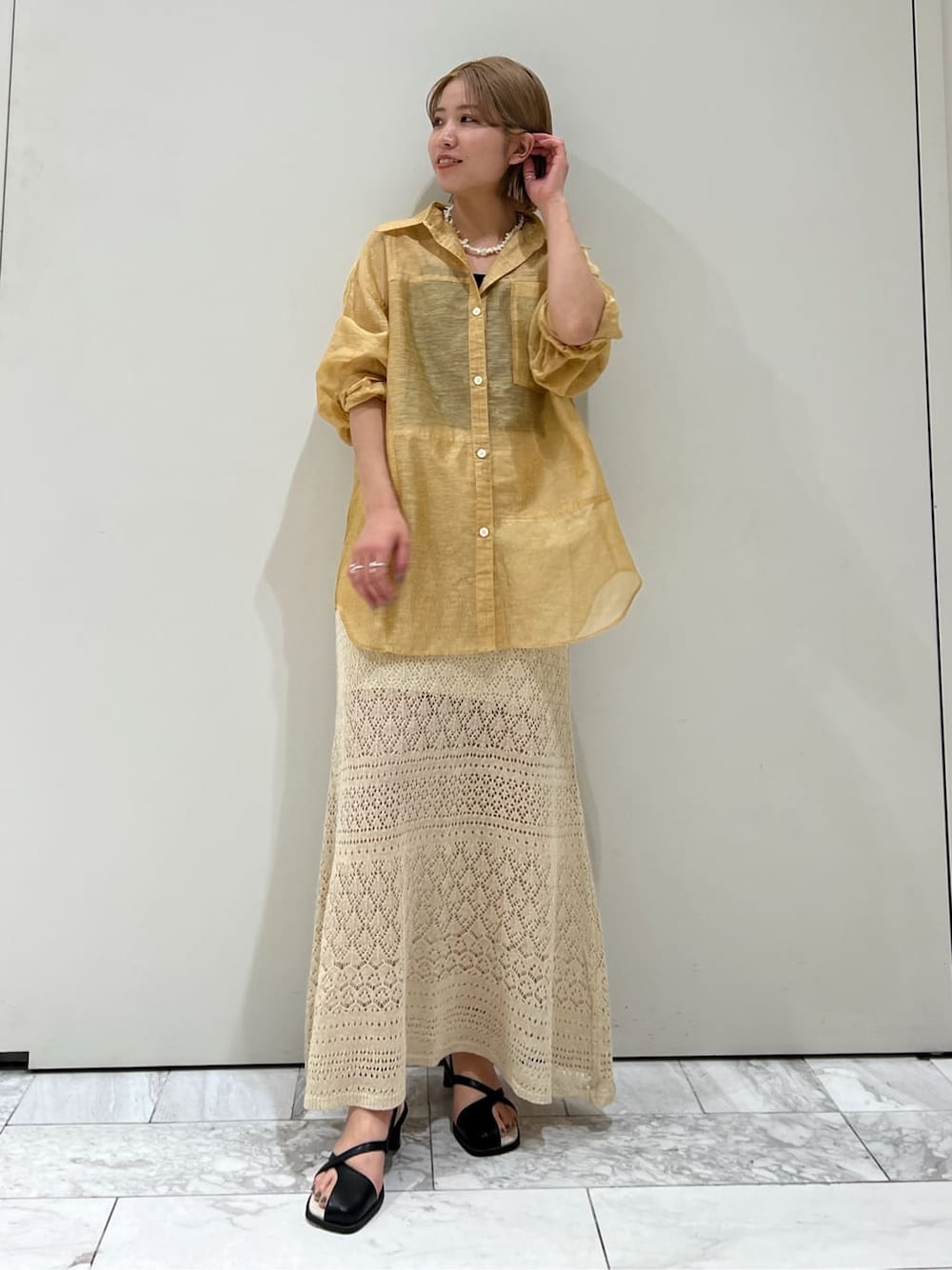 ブラウン系のシャツ/ブラウス、ベージュ系のスカート、ブラック系のサンダルを着用したレディースの春コーディネートの2枚目の写真