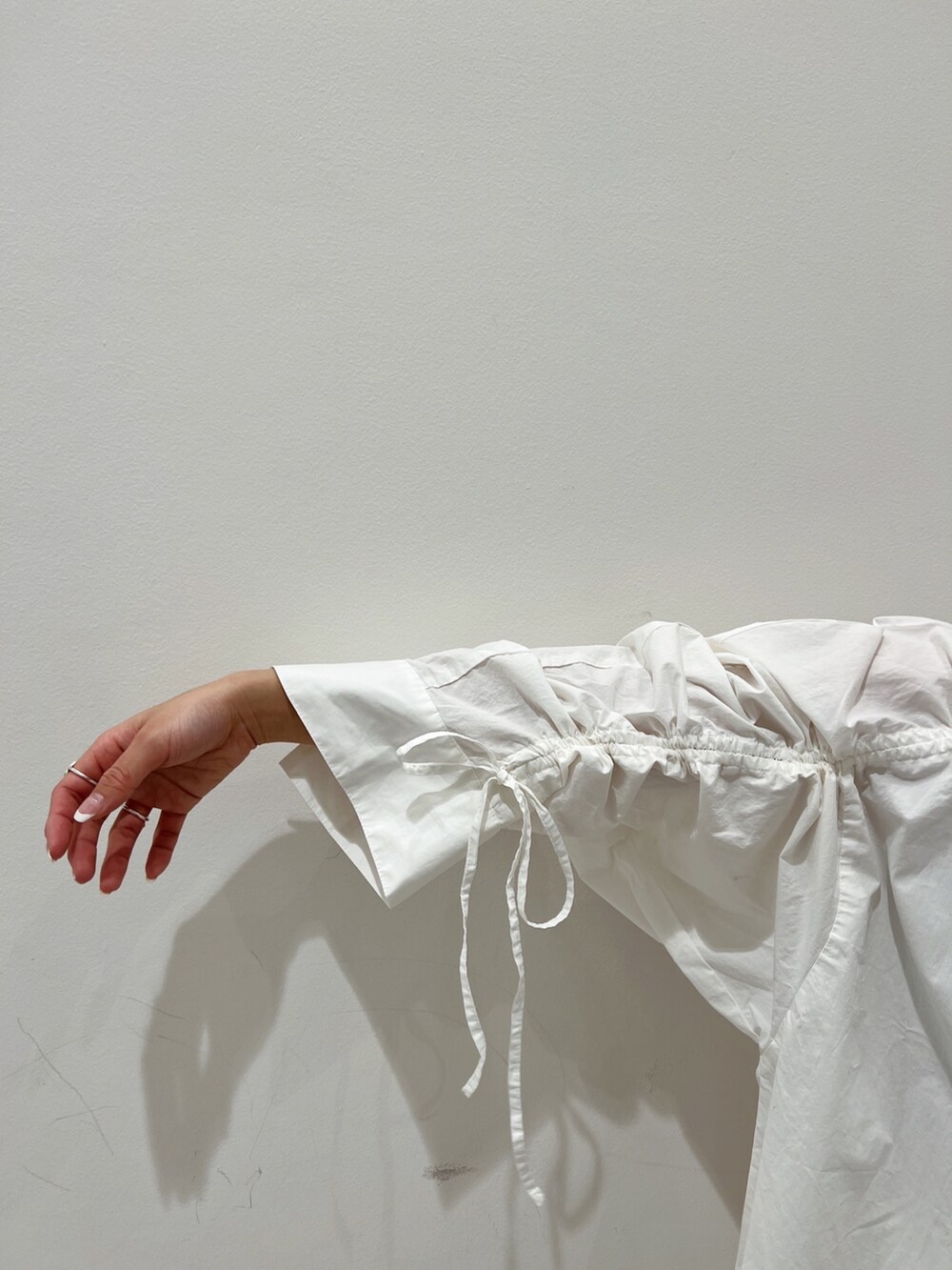 ホワイト系のシャツ/ブラウス、イエロー系のパンプス、ベージュ系のスカートを着用したレディースの冬コーディネートの8枚目の写真