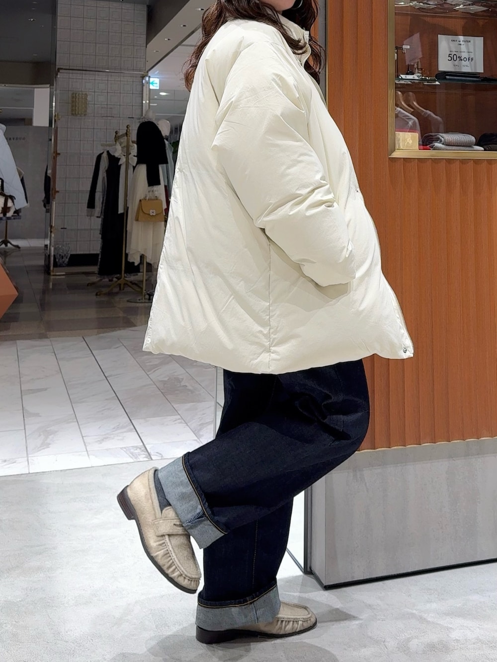 ホワイト系のダウンジャケット/コート、グレー系のニット/セーター、ブルー系のデニムパンツを着用したレディースの冬コーディネートの3枚目の写真