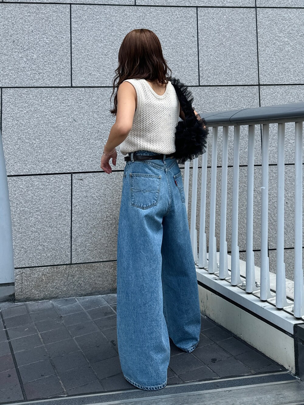 ブルー系のデニムパンツ、ホワイト系のニット/セーター、ブラック系のショルダーバッグを着用したレディースの秋コーディネートの3枚目の写真