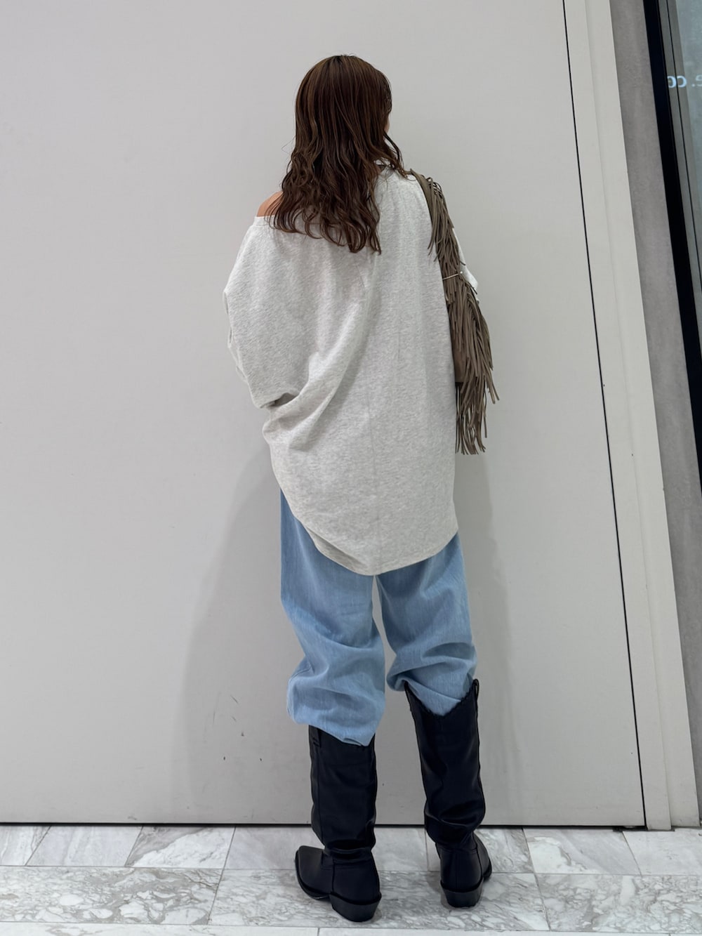 グレー系のTシャツ/カットソー、ベージュ系のハンドバッグ、ブルー系のデニムパンツを着用したレディースの春コーディネートの5枚目の写真