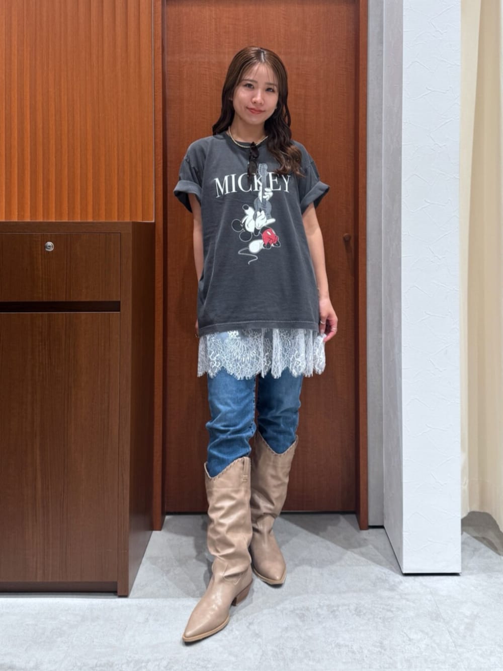 ベージュ系のブーツ、ブルー系のデニムパンツ、ホワイト系のキャミソールを着用したレディースの夏コーディネートの2枚目の写真
