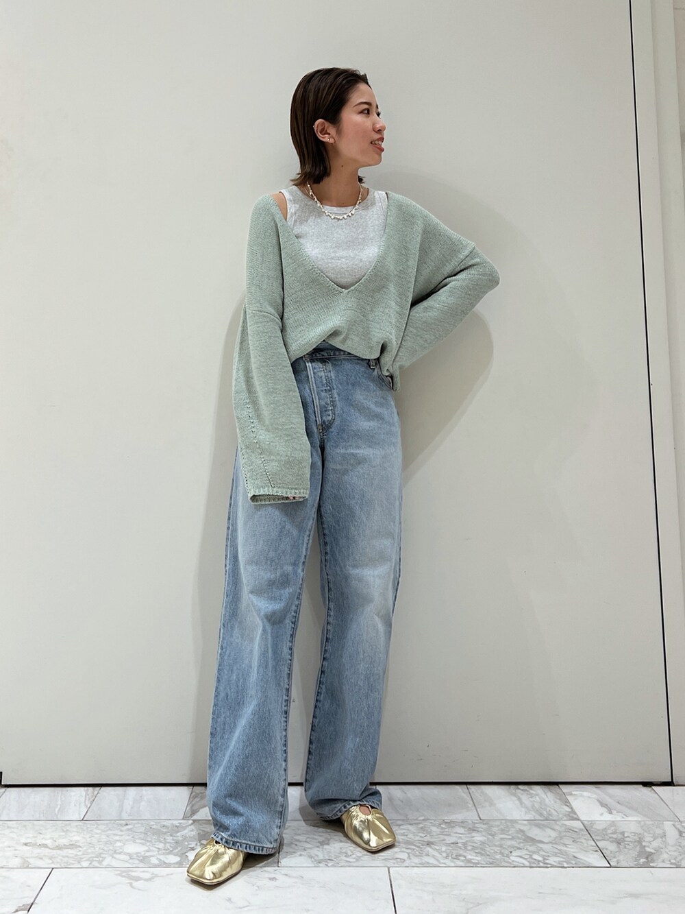 ブルー系のデニムパンツ、イエロー系のパンプス、グリーン系のニット/セーターを着用したレディースの冬コーディネートの2枚目の写真