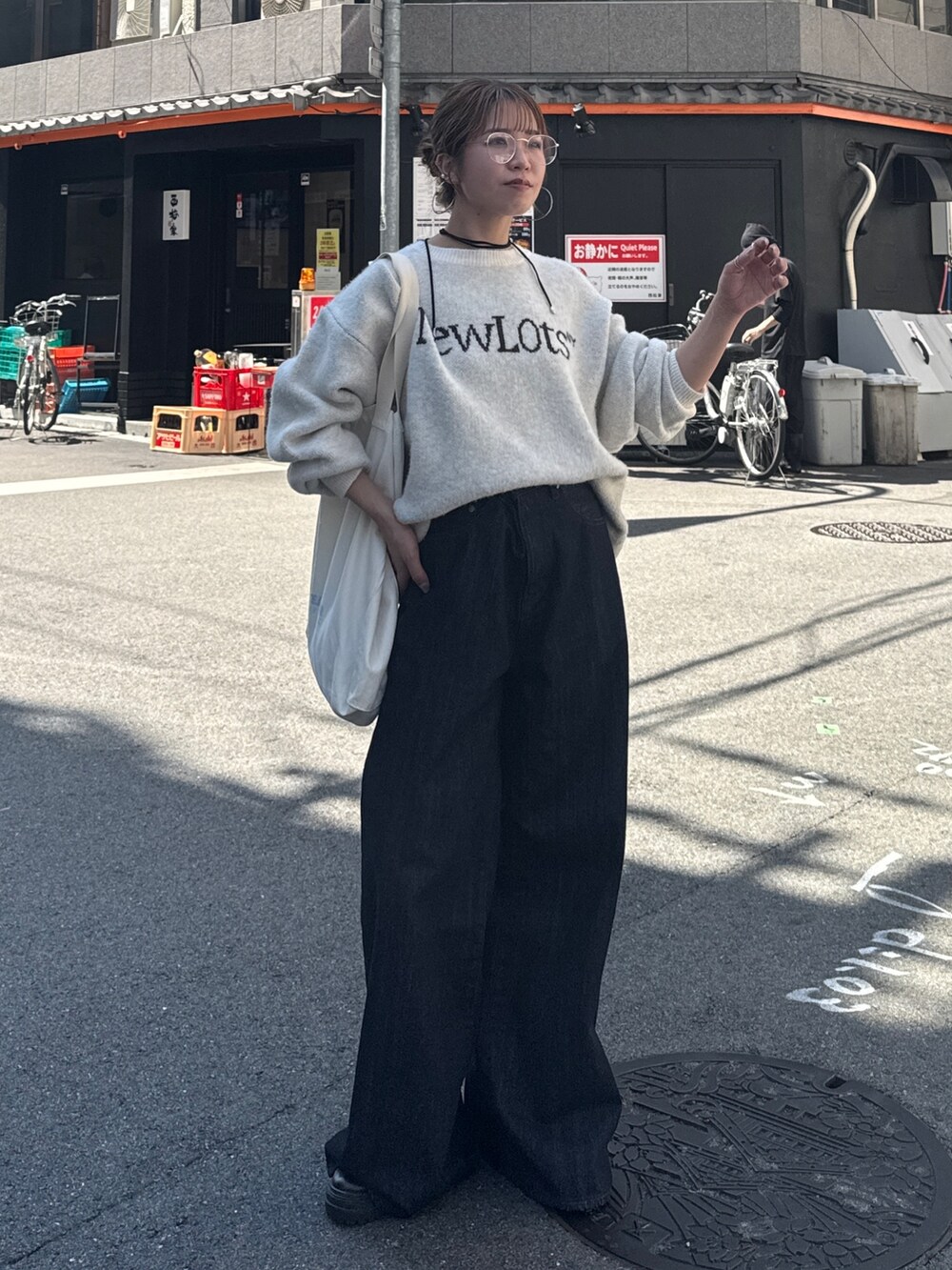 ブルー系のデニムパンツ、ホワイト系のニット/セーター、ホワイト系のトートバッグを着用したレディースの夏コーディネートの2枚目の写真